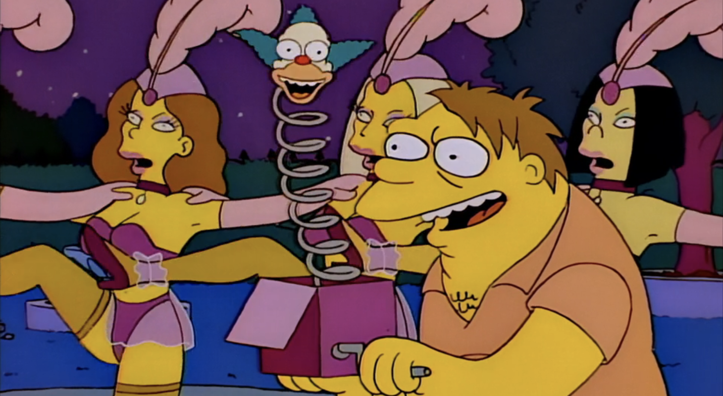 Barnie opens a jack-in-the-box in front of a line of kicking burlesque dancers.