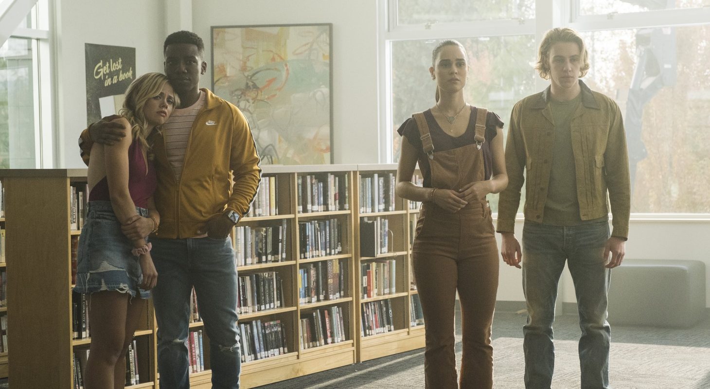 Four twenty-somethings stand in a library
