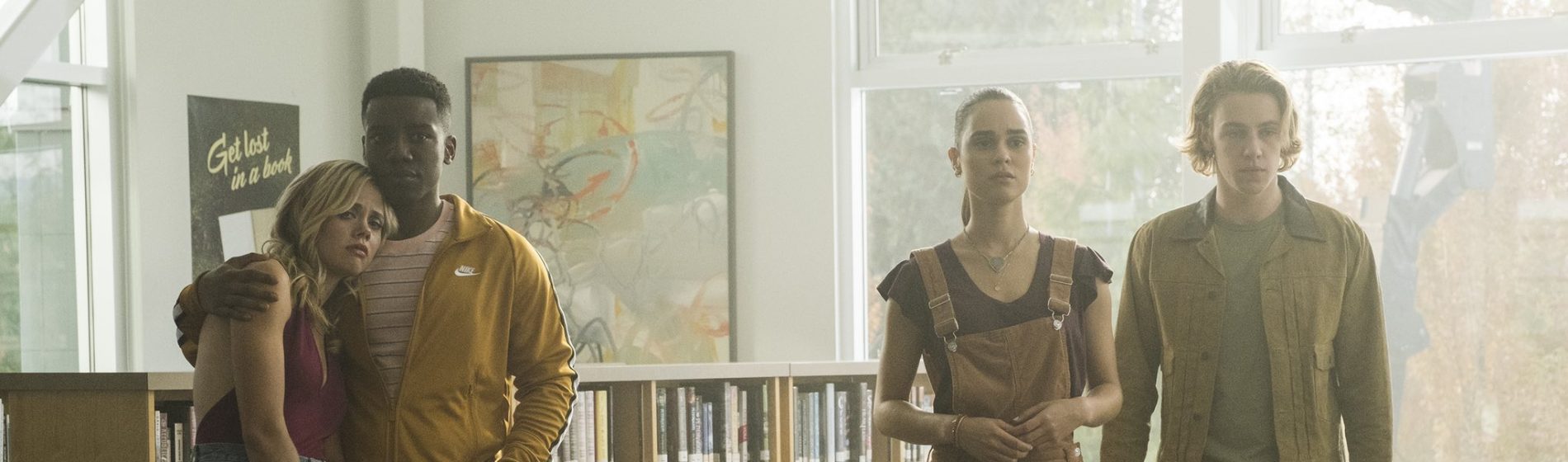 Four twenty-somethings stand in a library