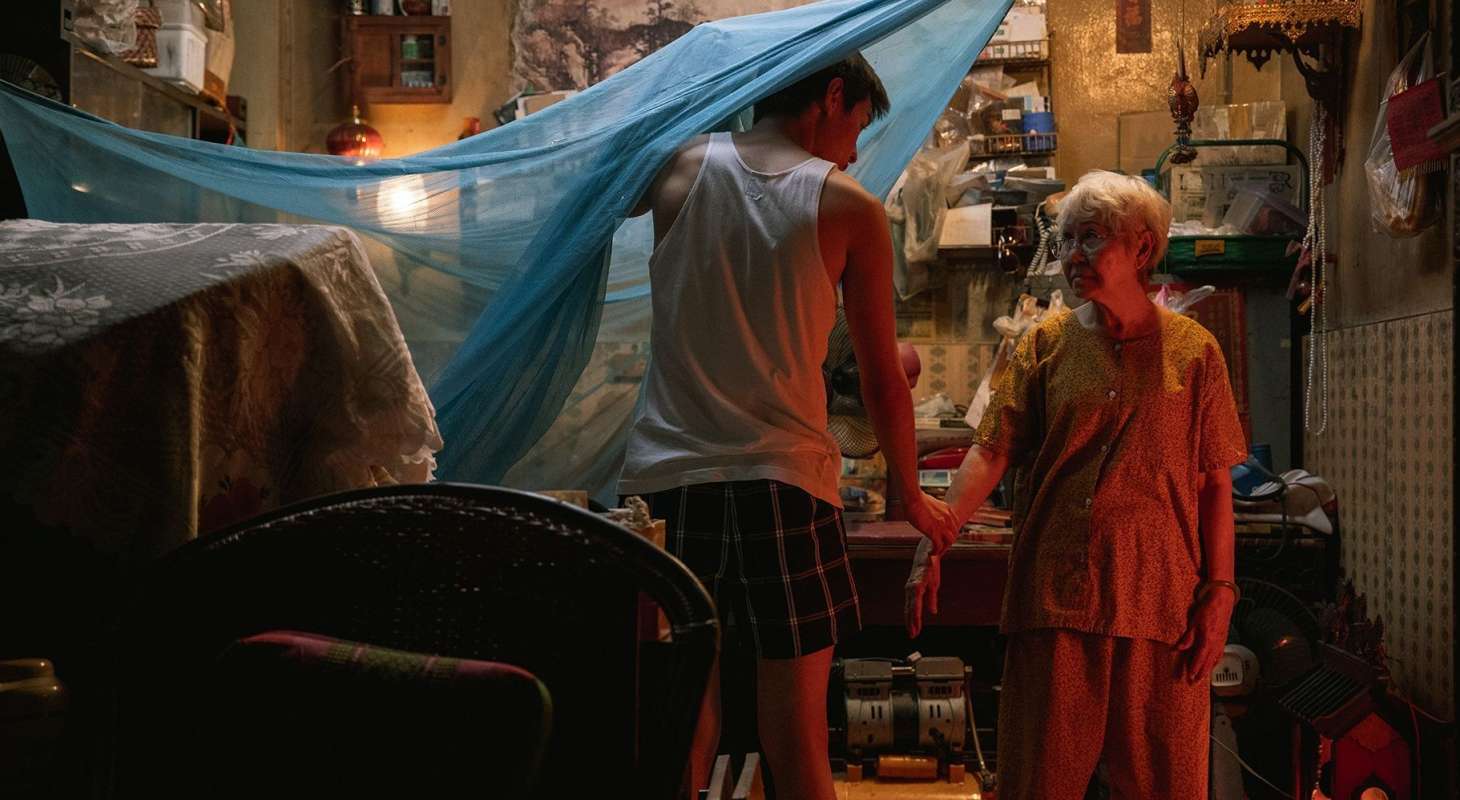 Putthipong "Billkin" Assaratanakul As M, holding hand of his on-screen gran