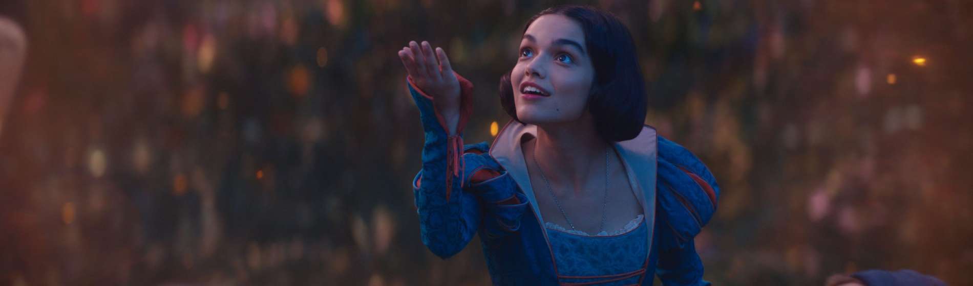 Rachel Zegler holds out her hand to the sky in Disney's SNOW WHITE.