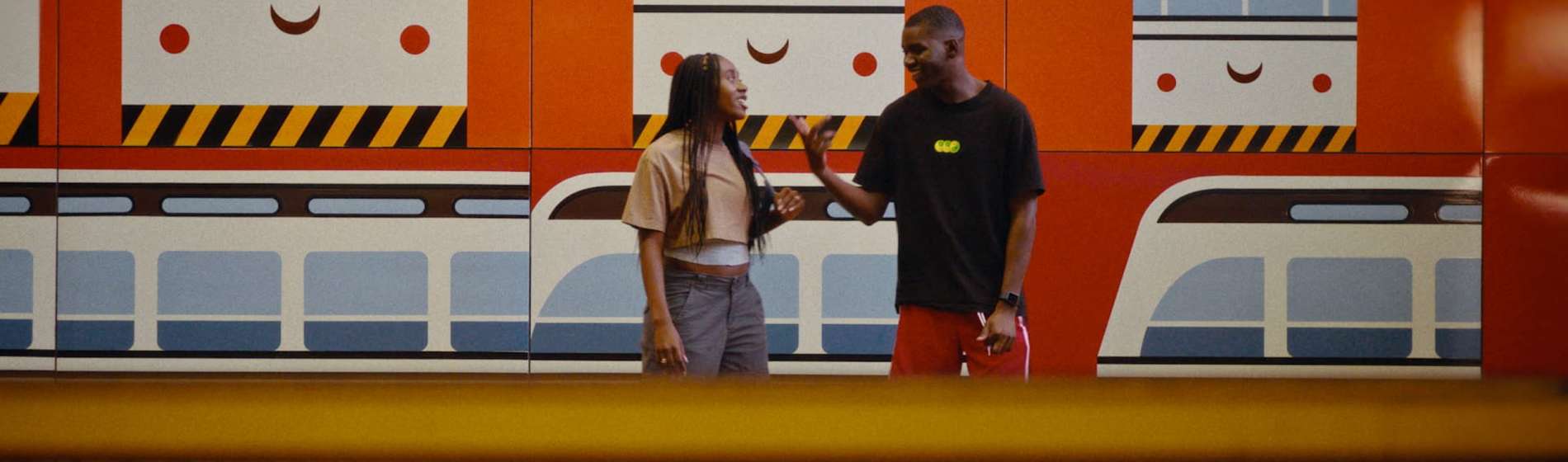 Two people stand in front of a train mural. Boxcutter film still.
