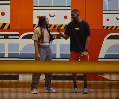 Two people stand in front of a train mural. Boxcutter film still.
