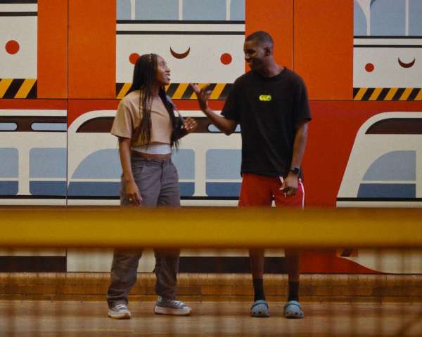 Two people stand in front of a train mural. Boxcutter film still.