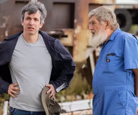 Nathan Fielder stands on an airport tarmac in an episode of the Rehearsal