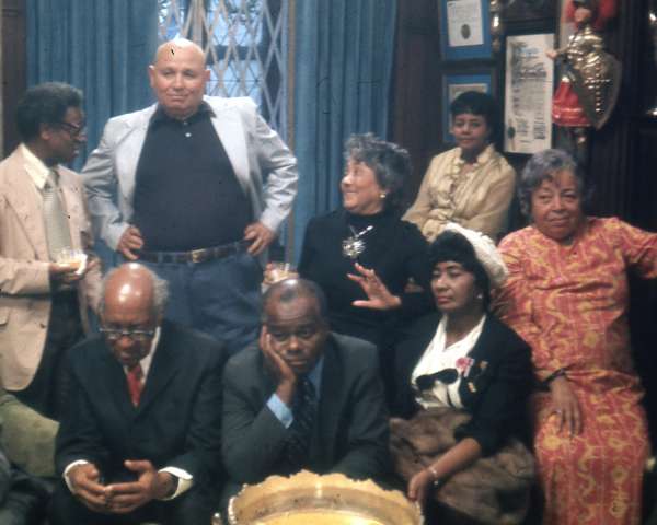 Sitting (left to right): Thomas Harvey, William Patterson, John Henrik Clarke, Mrs. J.B Matthews, Louise Patterson. Standing (left to right): Ernest Chrichlow, Romare Bearden, Ida Mae Cullen. | Photo by Bruce Stanford (1972), courtesy William Greaves Productions